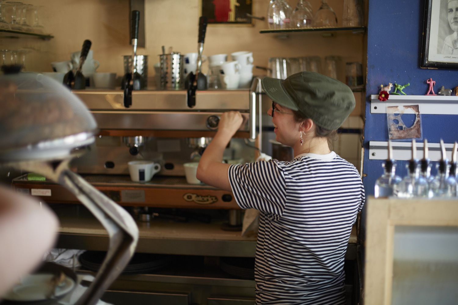 A barista in a striped shirt working the espresso machine behind the counter