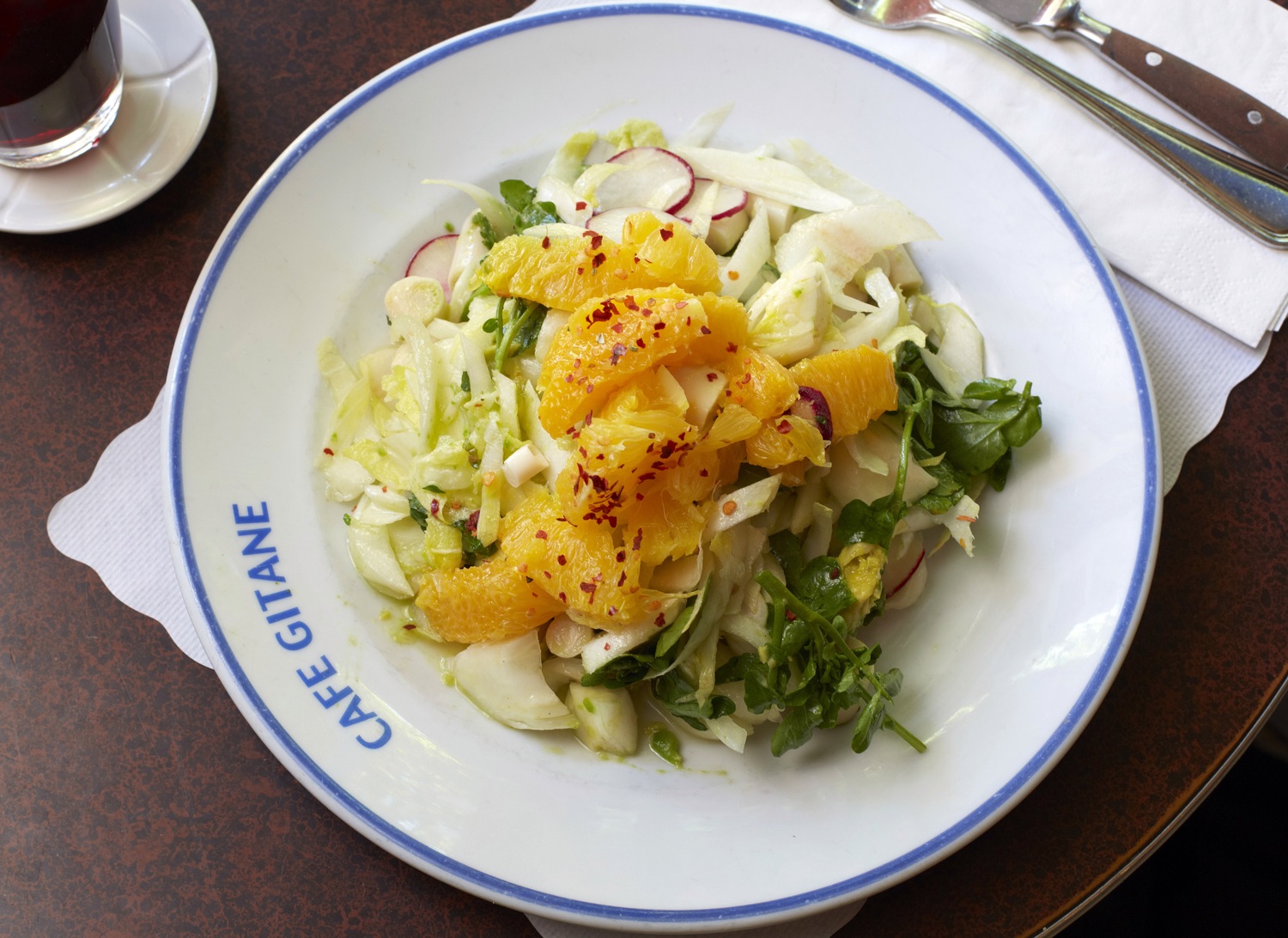 A salad of orange segments and greens on a Cafe Gitane plate