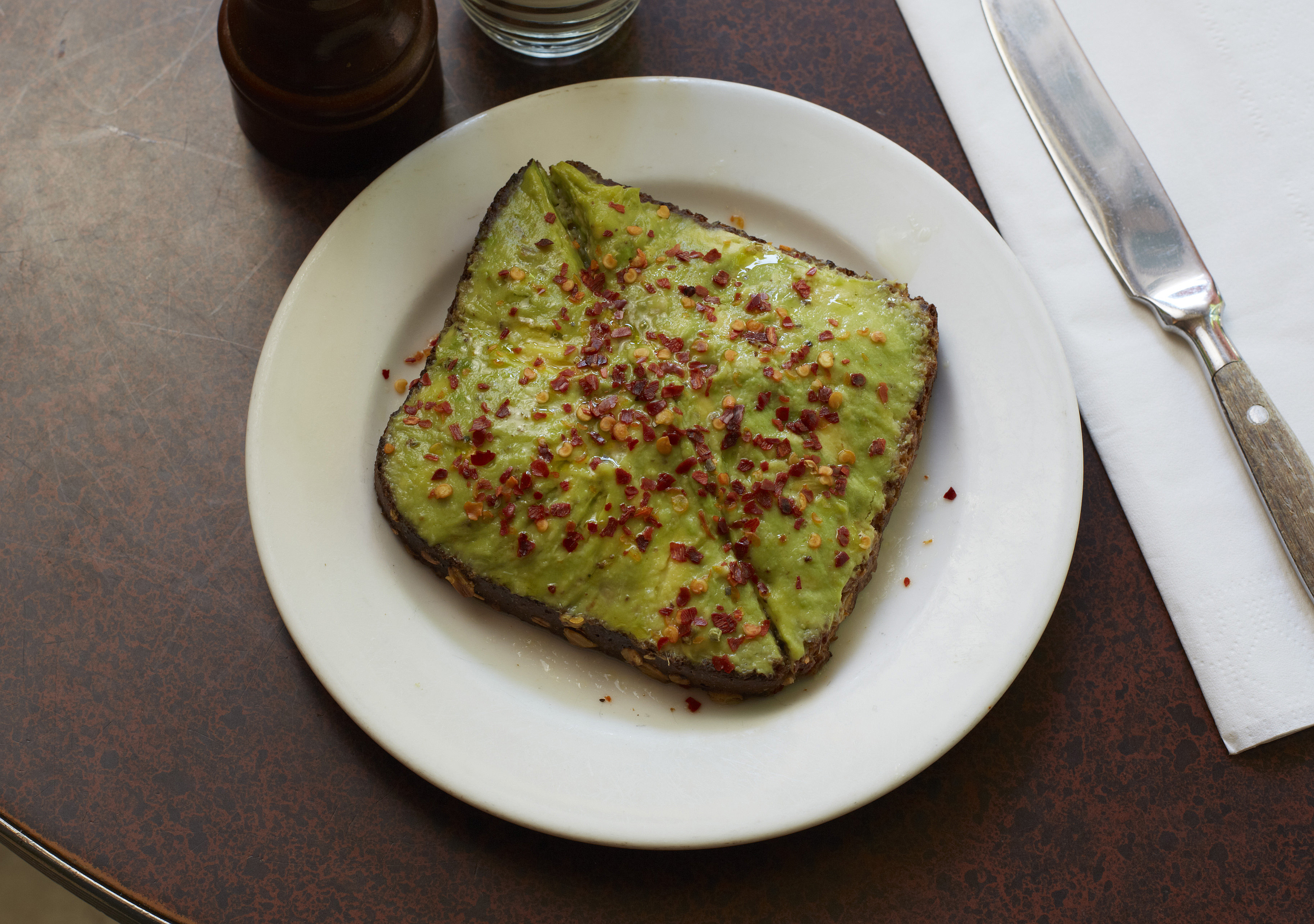 Avocado toast scattered with red chilli flakes on a white plate
