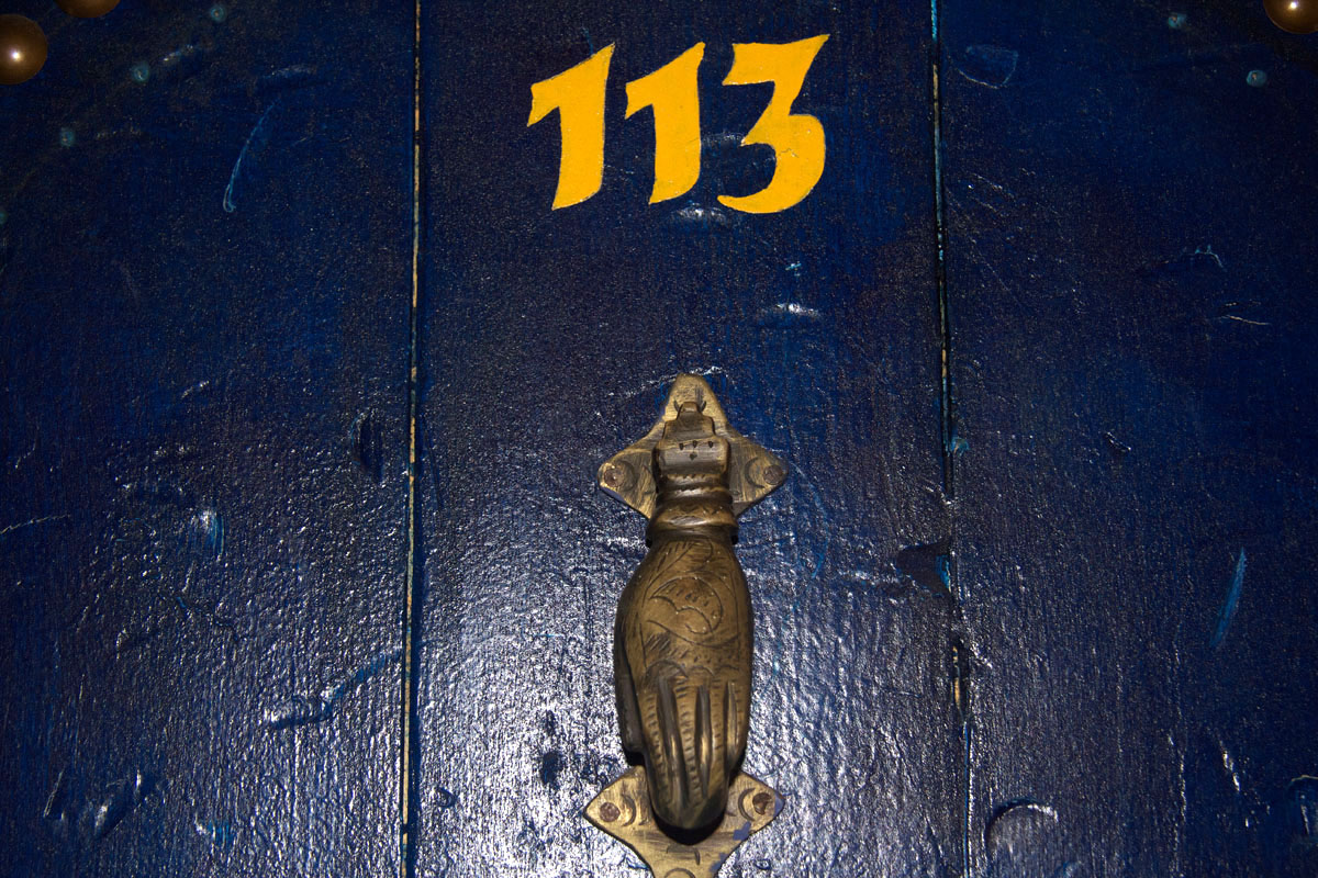 A deep blue painted door with gold number 113 and a figural knocker