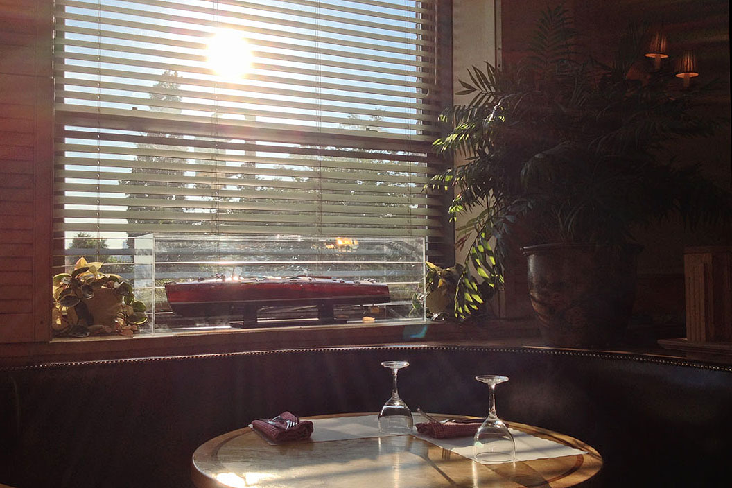 Late sunlight through venetian blinds above a banquette table