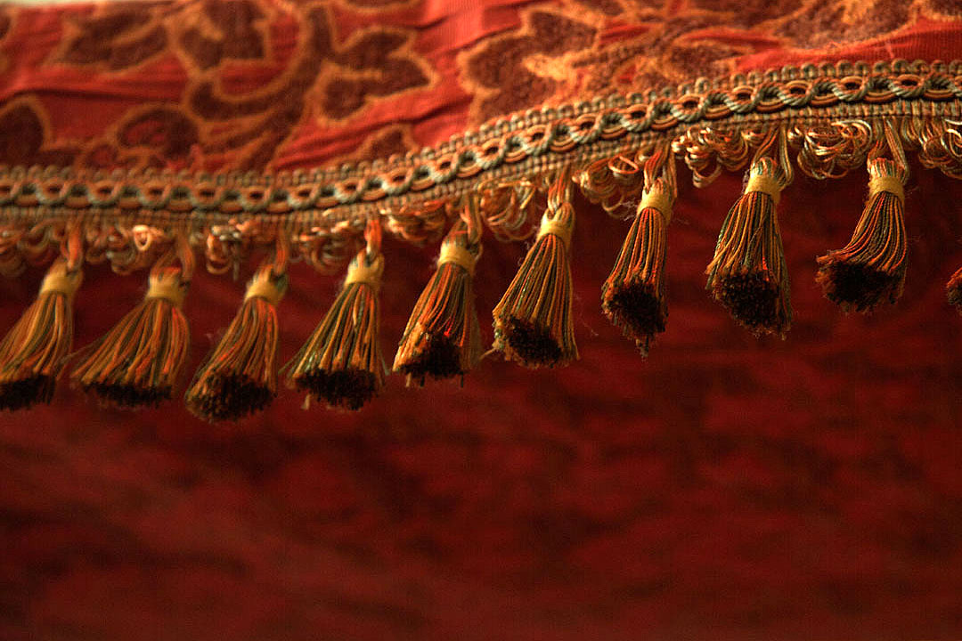 Gold tasselled fringe against deep red fabric