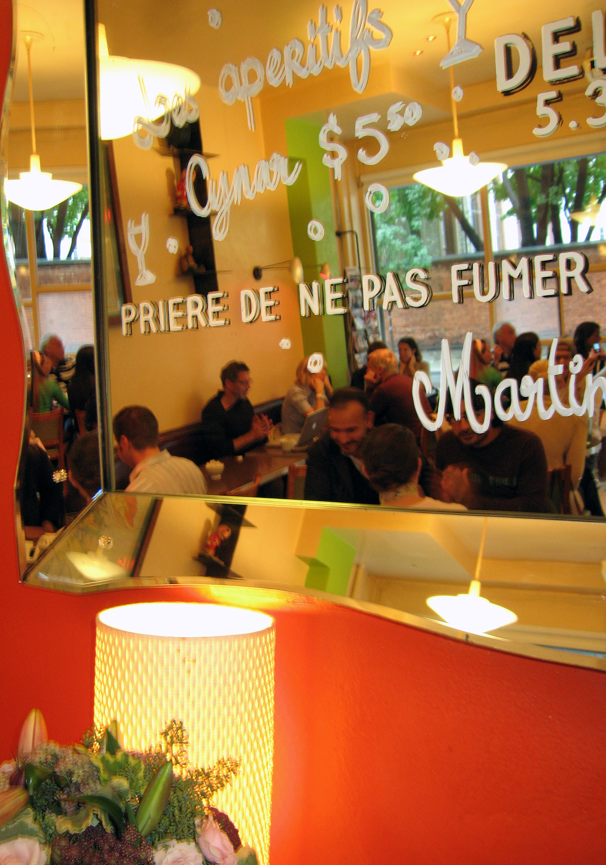 A busy cafe interior with ochre walls and a hand-painted no smoking sign