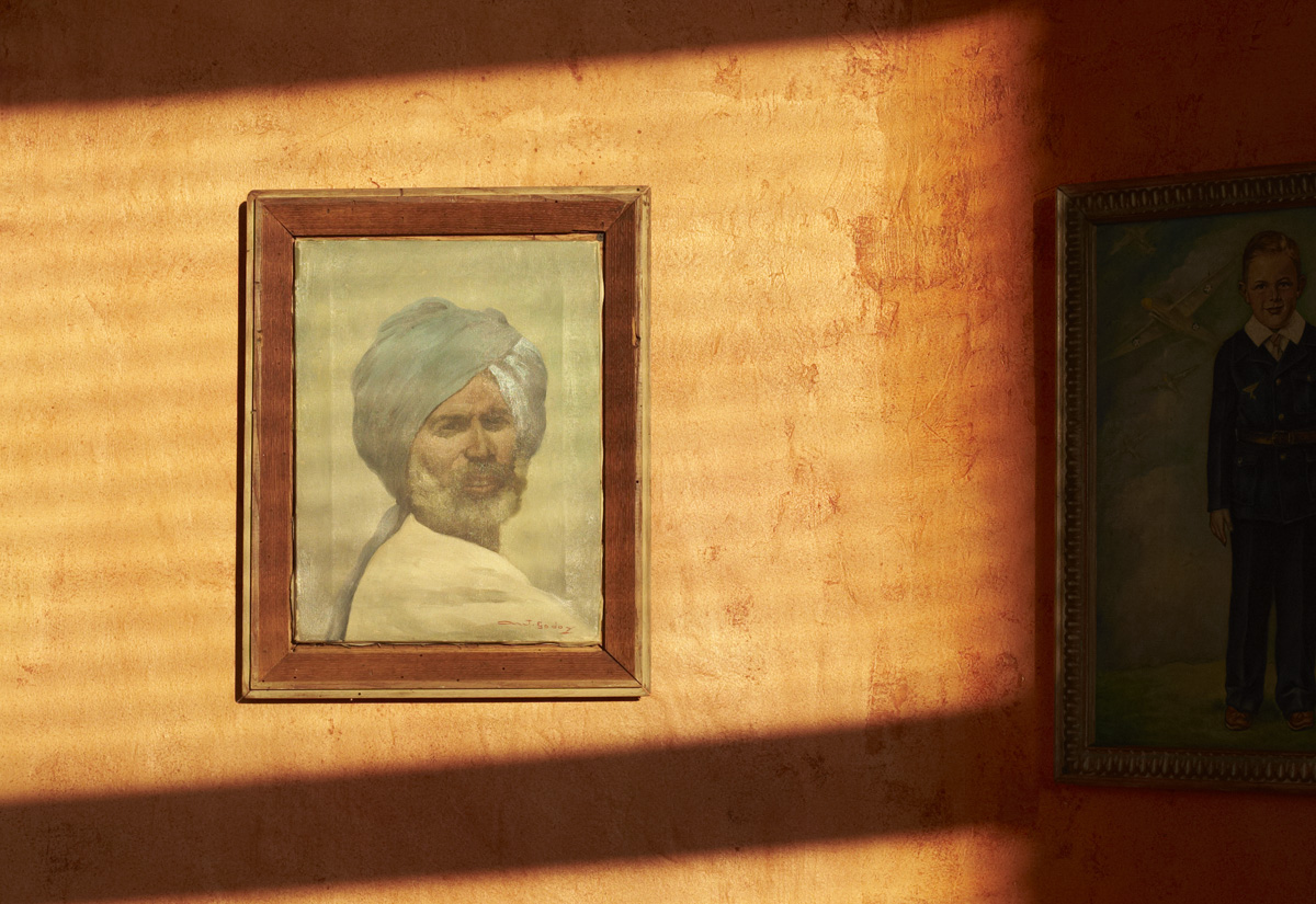 Two framed portraits hanging on an ochre wall