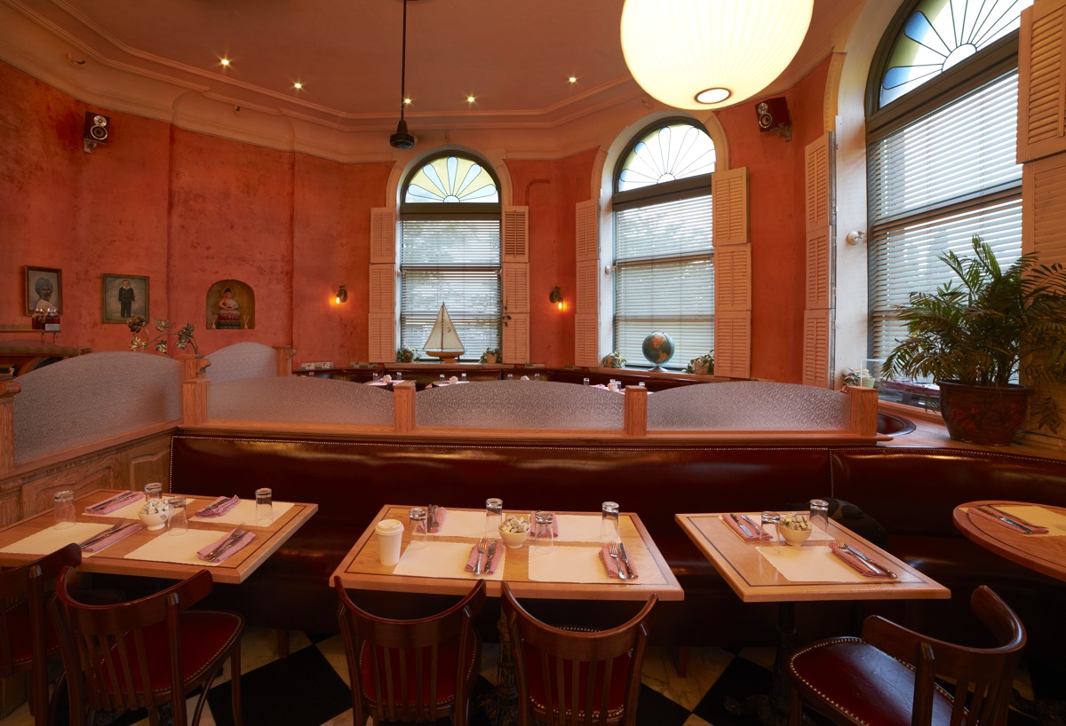 Banquette seating and set tables beneath tall arched windows
