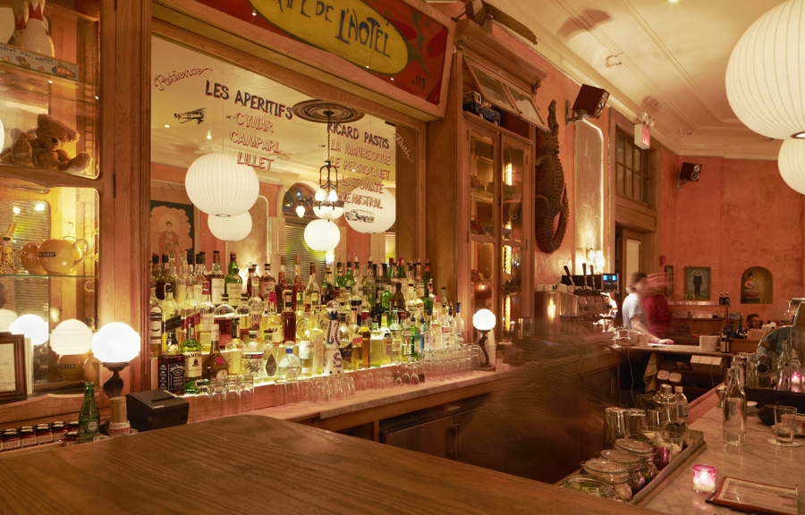 A bar lined with bottles beneath globe lights