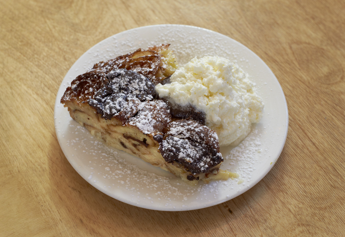 A slice of pastry dusted with icing sugar beside whipped cream