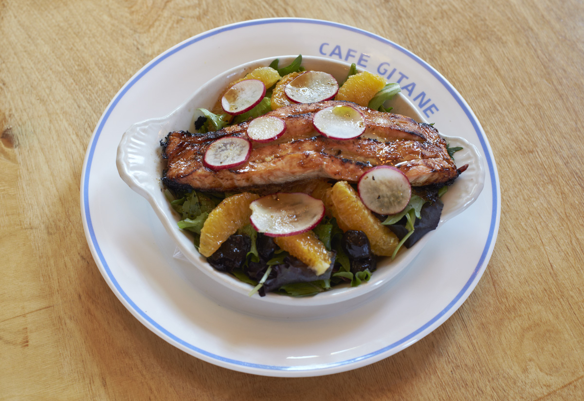 A composed salad with fish, quail eggs, greens and lemon on a Cafe Gitane plate