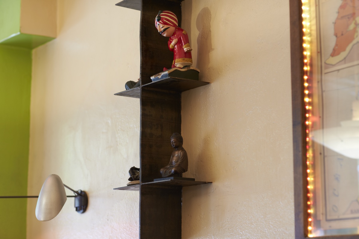 A shelf of small figures and a wall lamp against a pale green wall