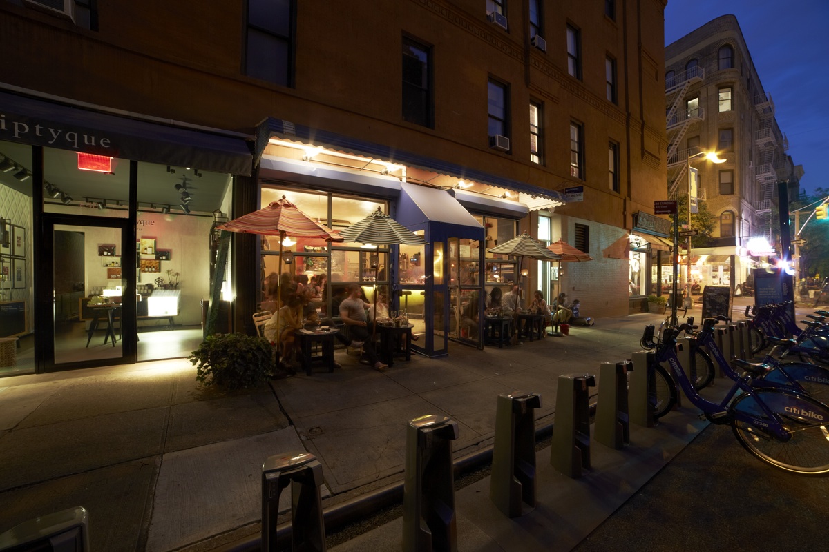 Mott Street at dusk, with shopfronts, awnings and parked bicycles